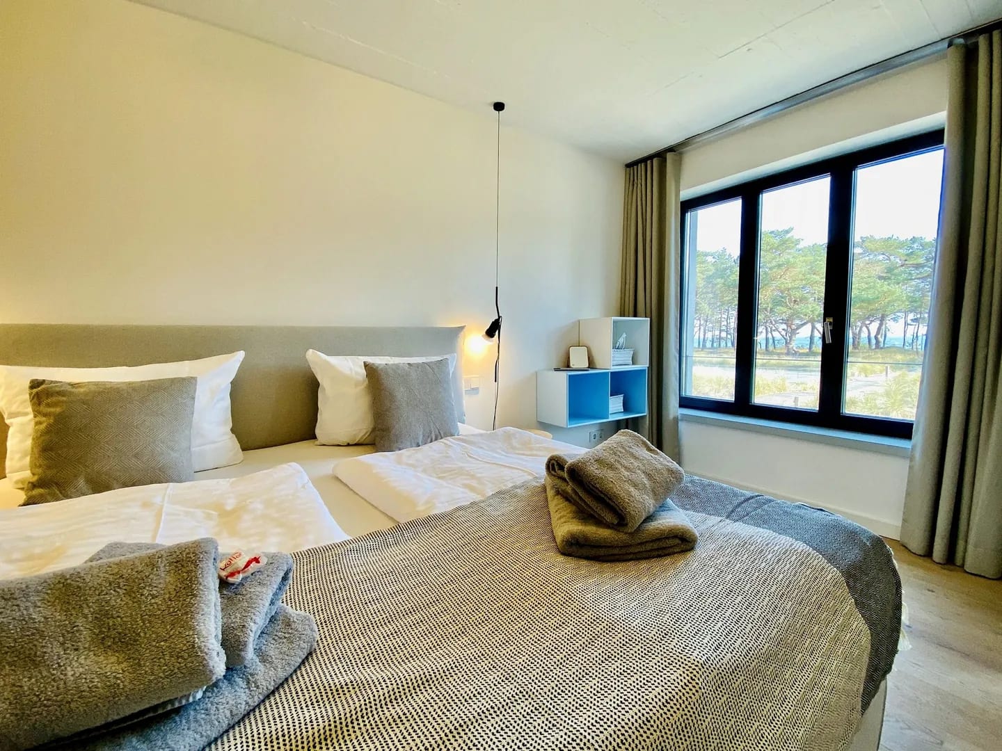 Vorher: Schlafzimmer mit Meerblick, zerknitterter Bettwäsche und gestapelten Handtüchern