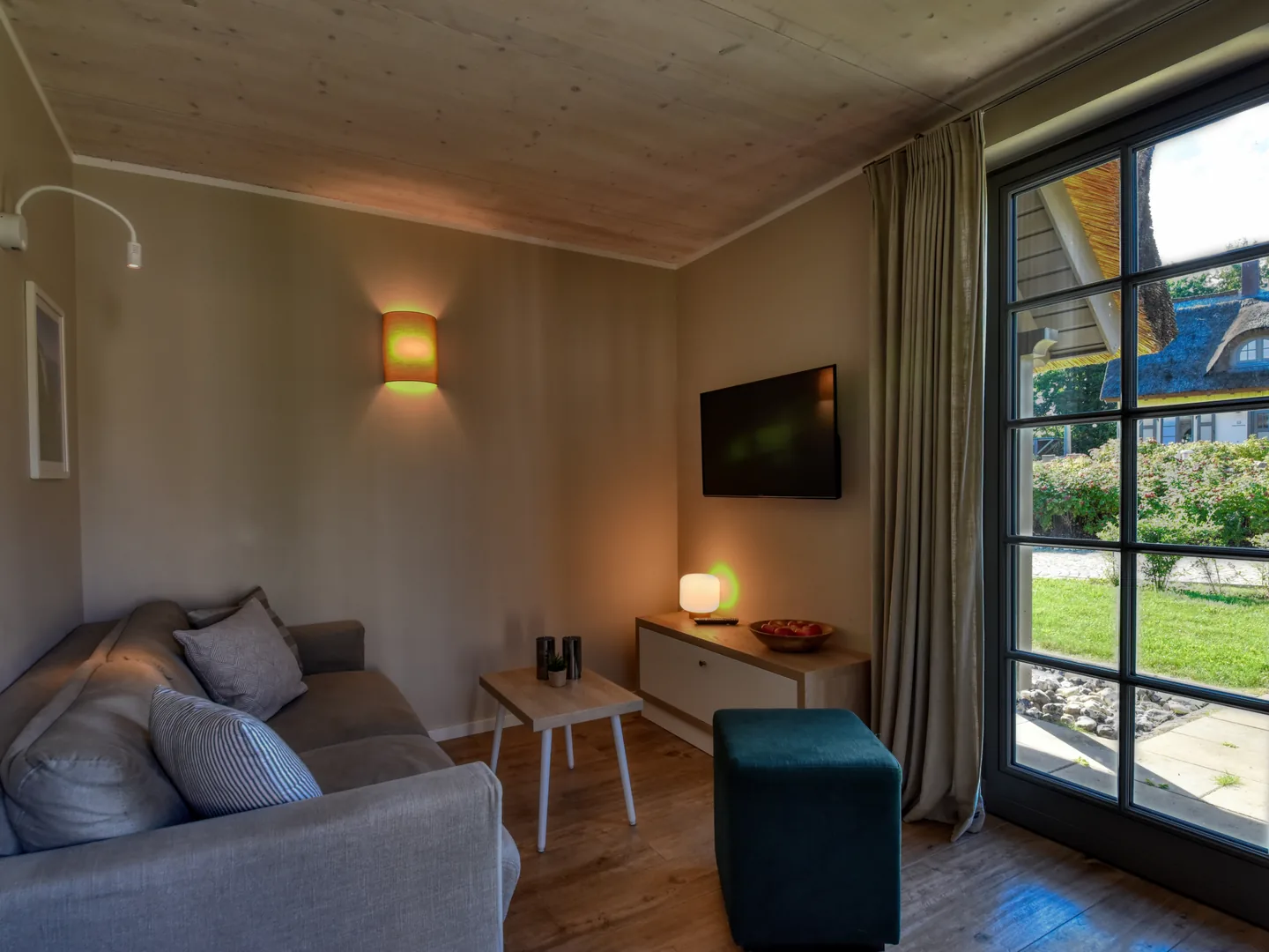 Vorher: dunkles Wohnzimmer mit Sofa, Fernseher und überstrahlter Terrassentür