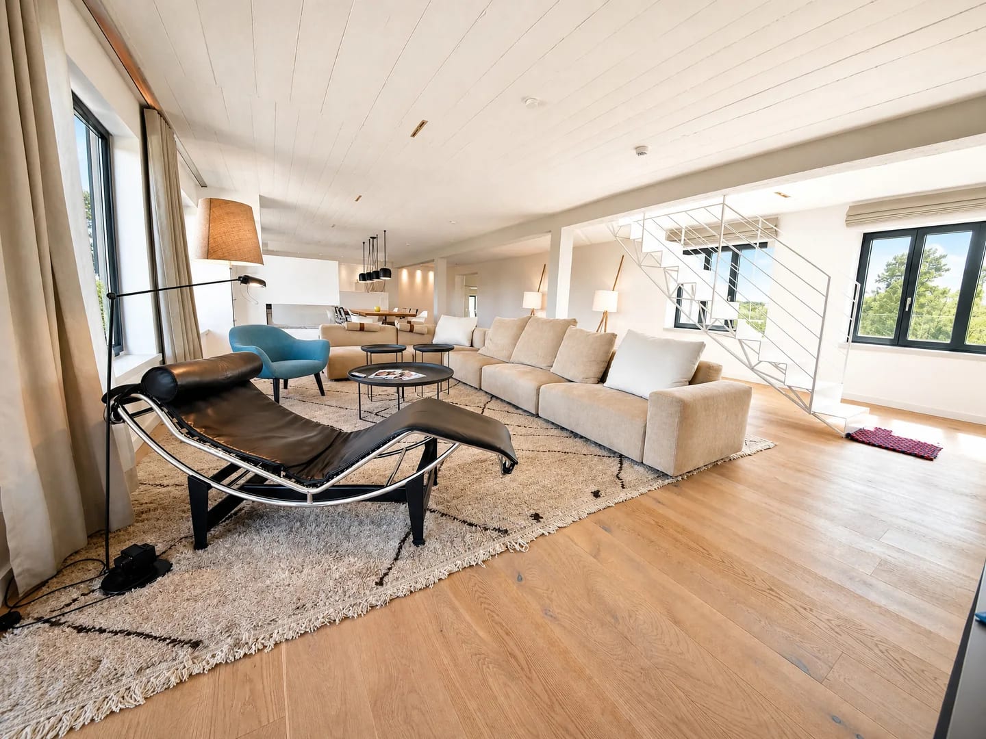 Nachher: Penthouse-Wohnzimmer mit hellerem Raumgefühl, Sofa, Treppe und Fensterfront